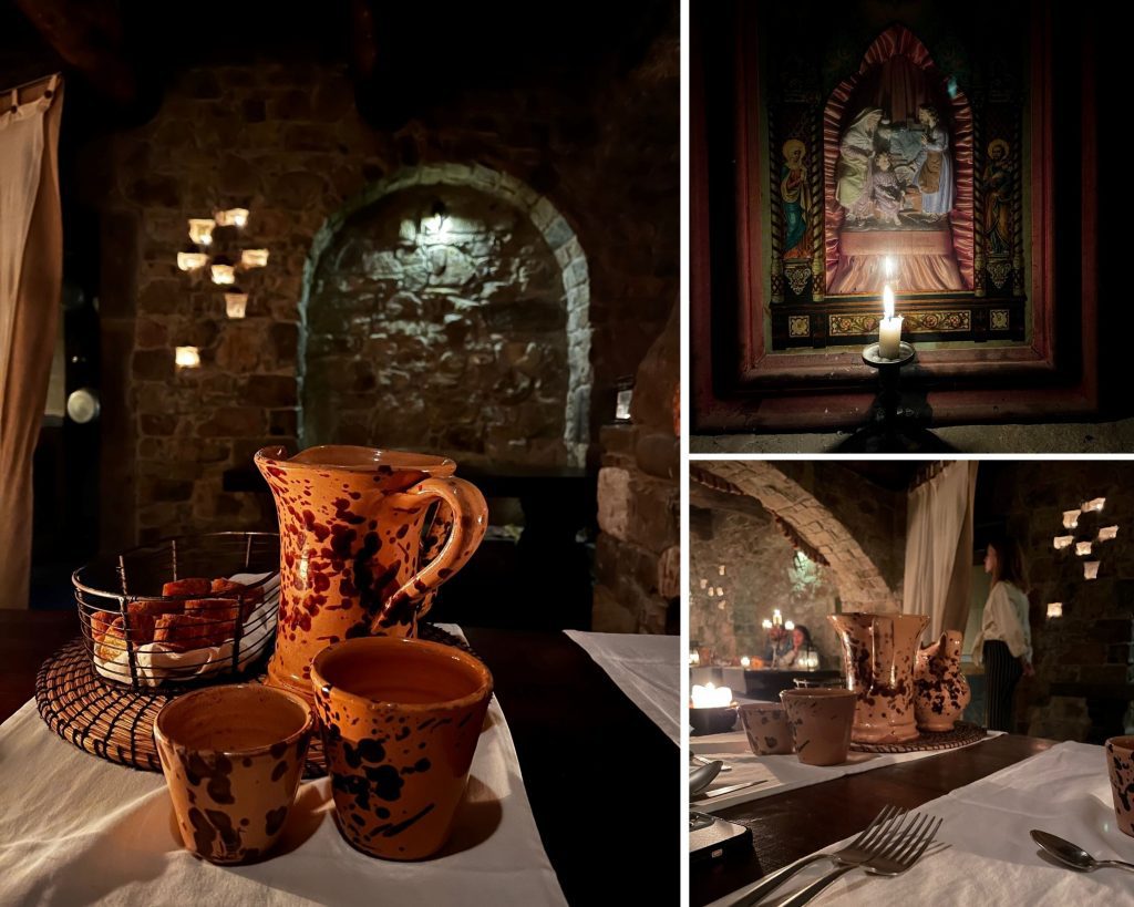 This image presents a collage of three photographs showcasing a medieval-style dining room, with the leftmost photo featuring a prominent display of two large orange ceramic jugs alongside two small cups on a white tablecloth. The top right photograph highlights a vibrant stained glass window or painting adorning the wall above a lit candle. The bottom right image offers an expansive view of the room, revealing the same ceramics on a long wooden table accompanied by silverware and a person walking towards the camera in the background. Together, these images evoke the atmosphere of a medieval-style banquet hall or castle dining area, exuding a warm and welcoming ambiance with its dark colors, candles, and rustic decorations.