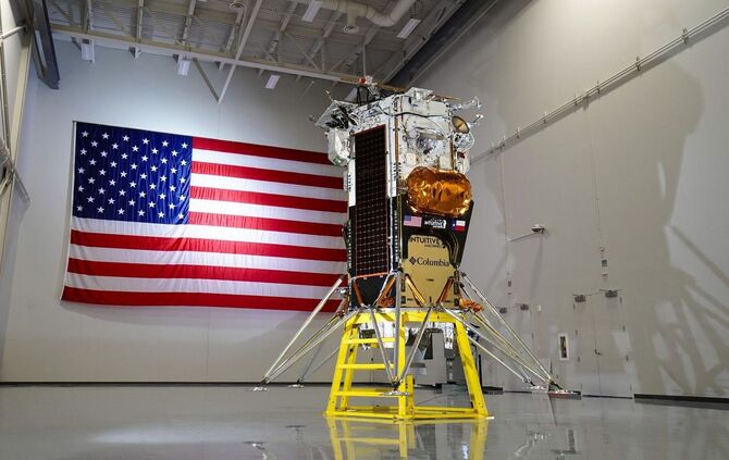 The image depicts a large American flag hanging on the wall of a room, with a satellite in the foreground. * **American Flag** * The flag is hung horizontally on the wall. * It features red and white stripes with blue stars in the upper left corner. * The flag appears to be made of fabric or vinyl material. * **Satellite** * The satellite is positioned in front of the flag, facing towards it. * It has a cylindrical body with solar panels attached to its sides. * A large antenna protrudes from the top of the satellite. * The satellite appears to be made of metal and plastic materials. * **Room** * The room has white walls and a shiny floor. * There are no other objects or people visible in the image. In summary, the image shows an American flag hanging on the wall of a room, with a satellite positioned in front of it. The satellite has a cylindrical body with solar panels and an antenna, and appears to be made of metal and plastic materials.