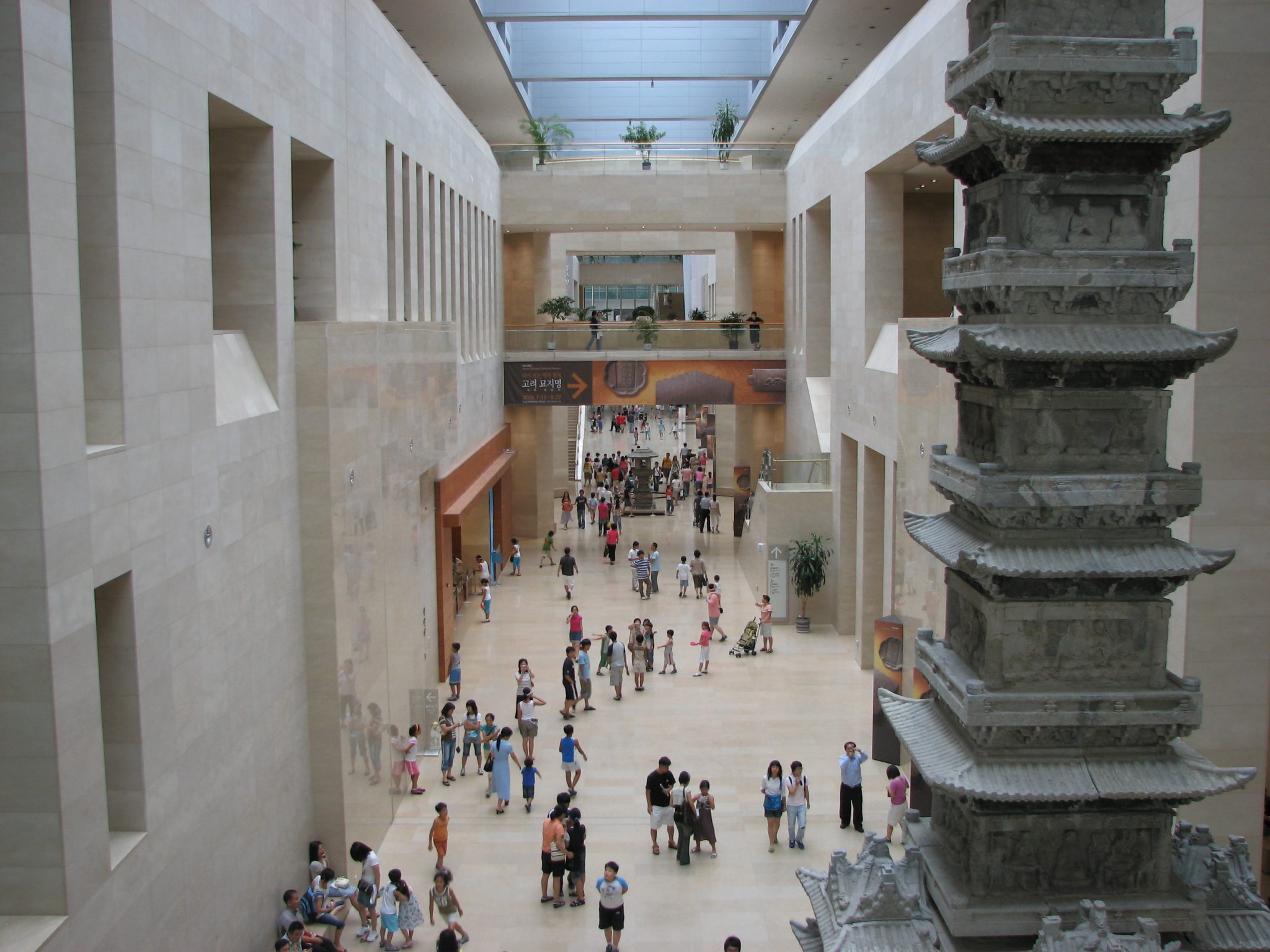 Alt tag: "Interior view of a spacious museum featuring a modern design with natural light, displaying a large pagoda sculpture and crowds of visitors exploring the exhibits."