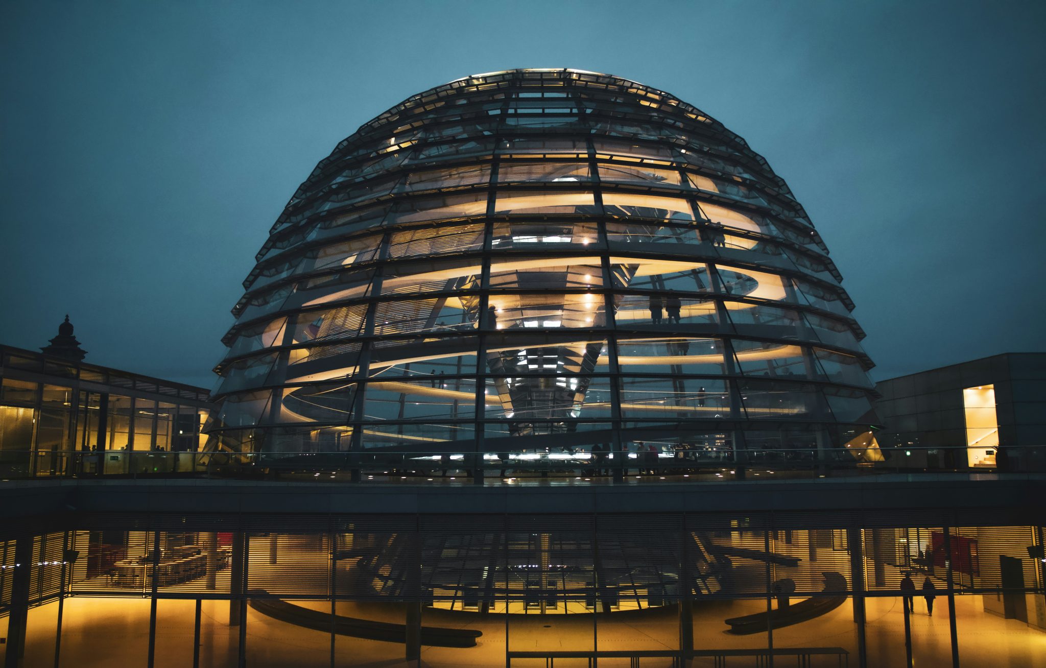 The Berlin Reichstag glass dome at dusk, featuring a large circular structure made of transparent glass and steel. **Key Features:** * The dome's upper section is open to the sky. * Below it lies an observation deck with 360-degree views of the city. * A spiral walkway leads visitors from one side of the dome to the other.