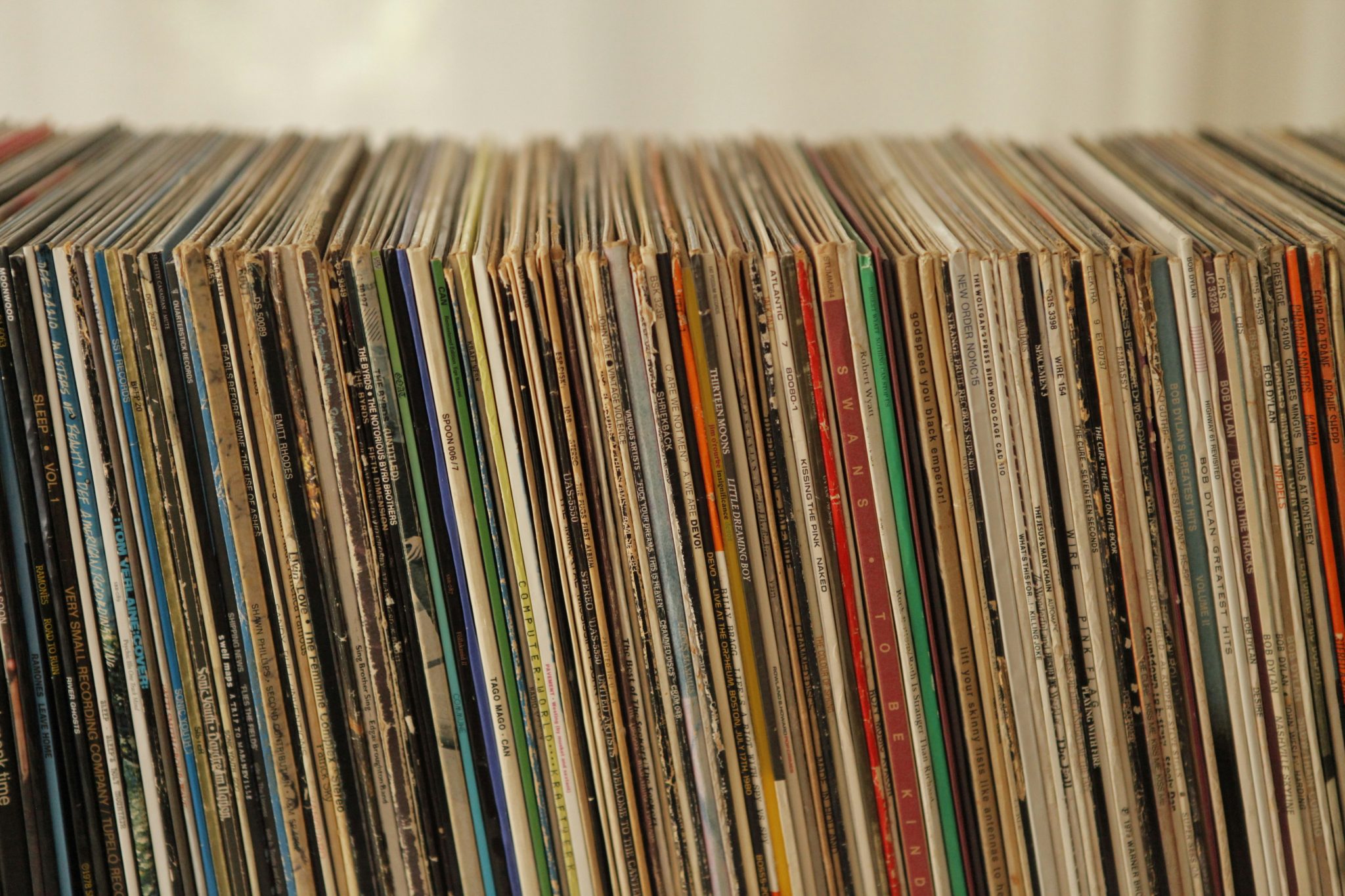 A close-up view of a collection of vinyl records, showcasing colorful album covers and varied designs, stacked neatly on a shelf.